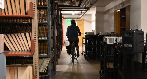 iLearnNH team member bicycles through the library
